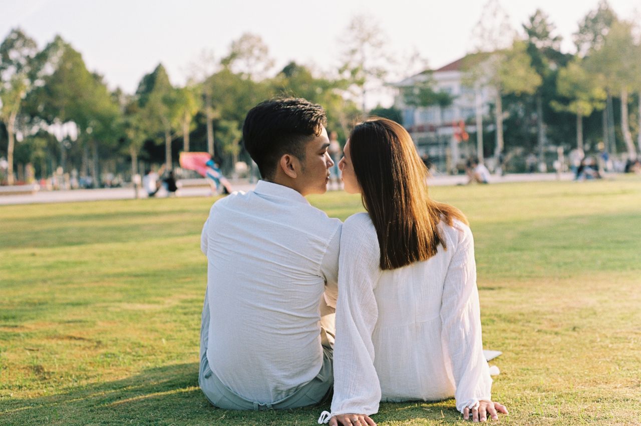 A loving couple enjoys a peaceful day in the park, sitting closely on the grass.